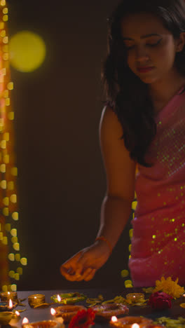 Vertical-Video-Shot-Of-Woman-Lighting-Diya-Oil-Lamps-Celebrating-Festival-Of-Diwali-In-Slow-Motion